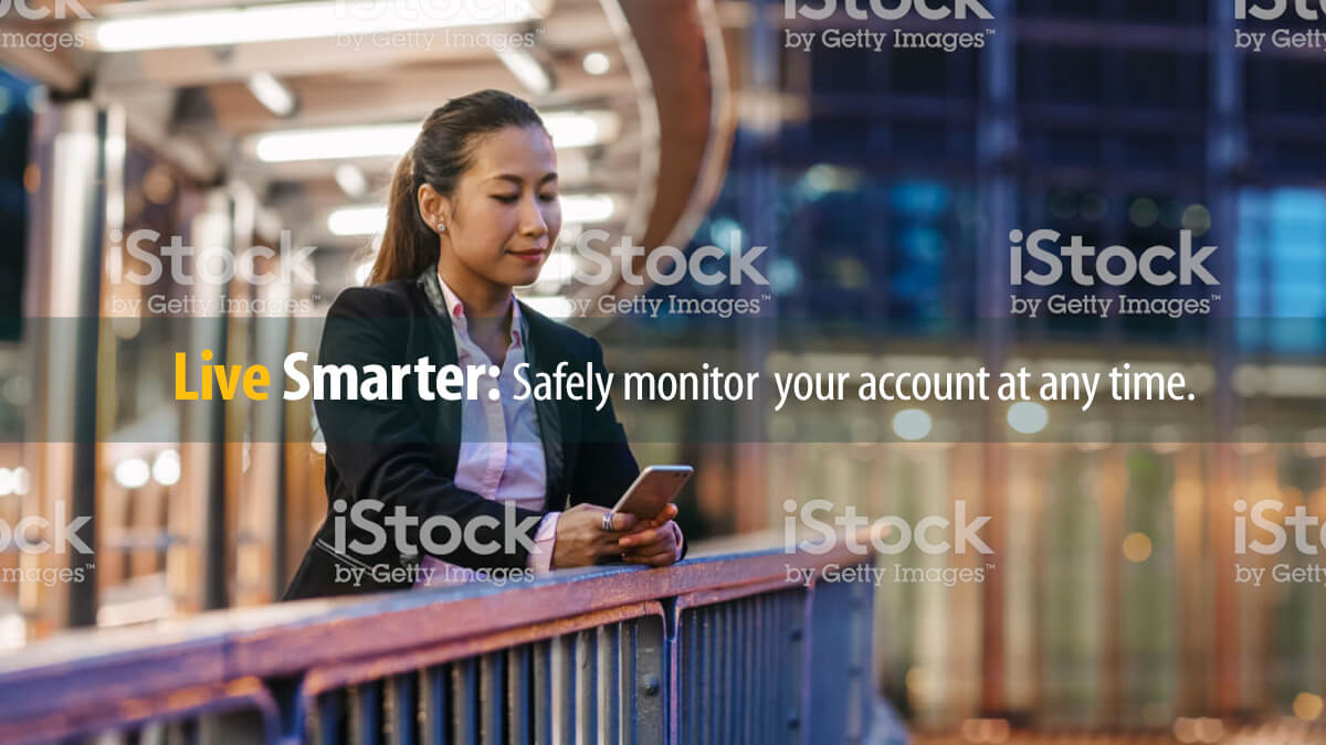 A woman uses her phone to access automated phone banking while away from home